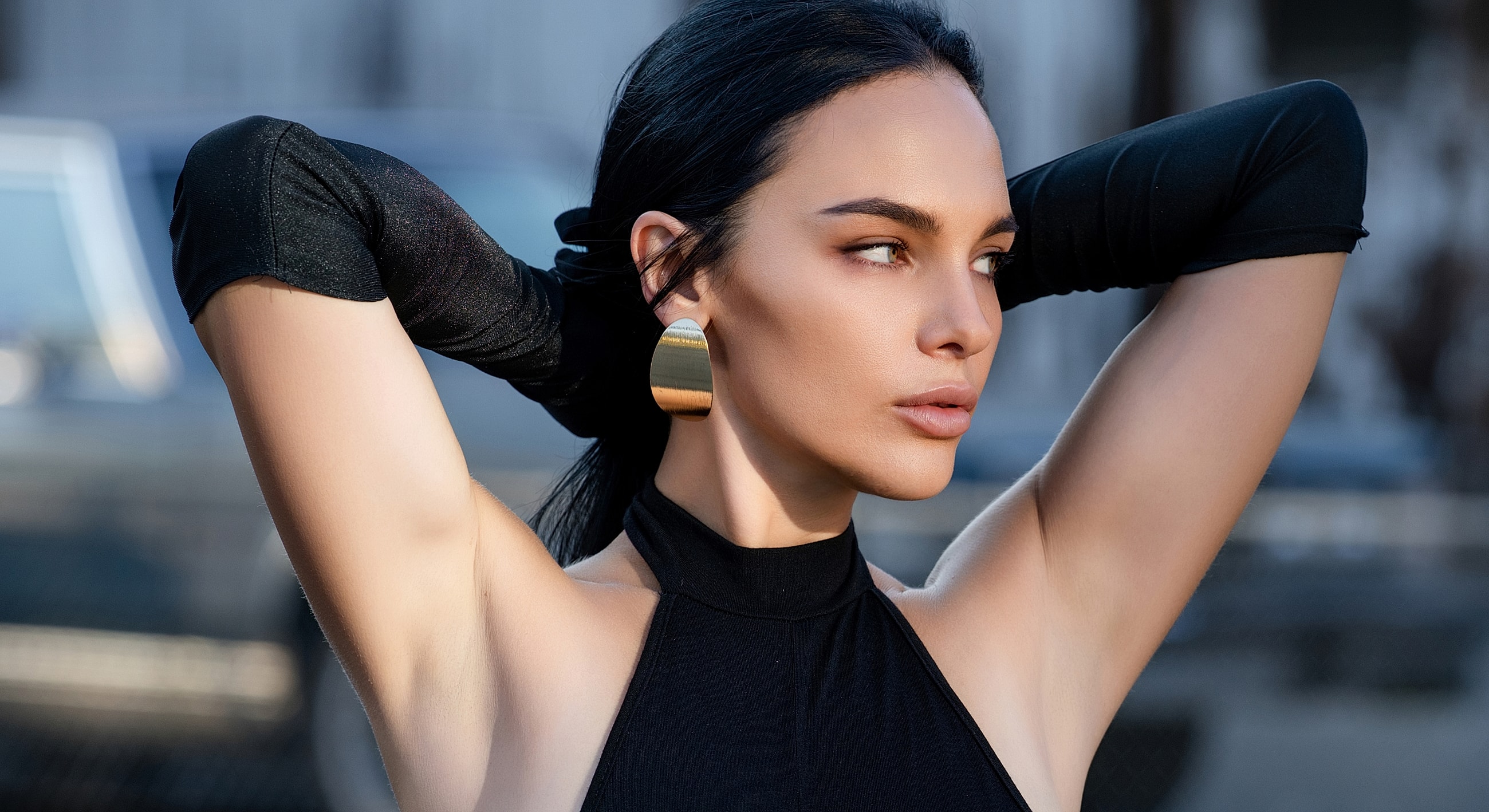 Model in black outfit with large earrings.