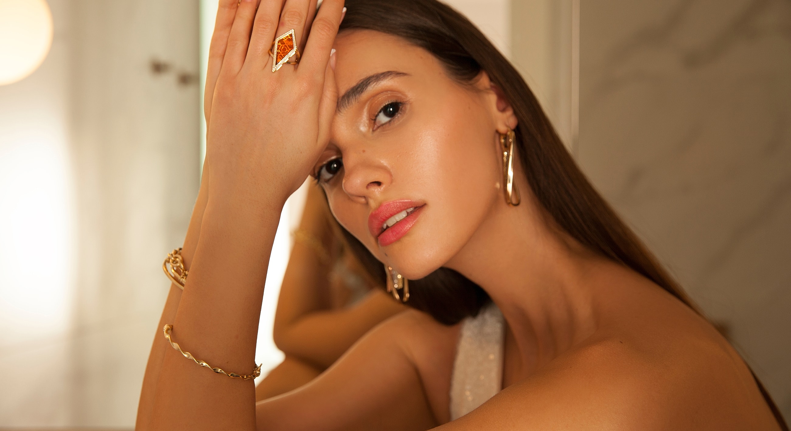 Woman showcasing elegant jewelry and makeup.